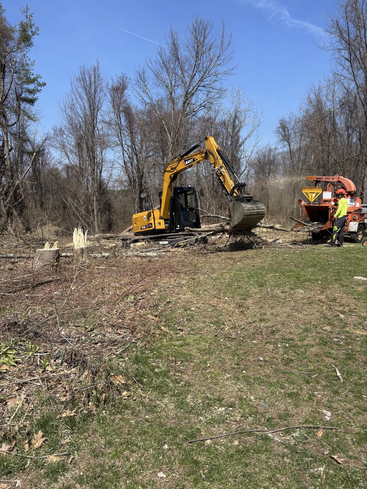 Excavator pushing brush, chipper truck behind